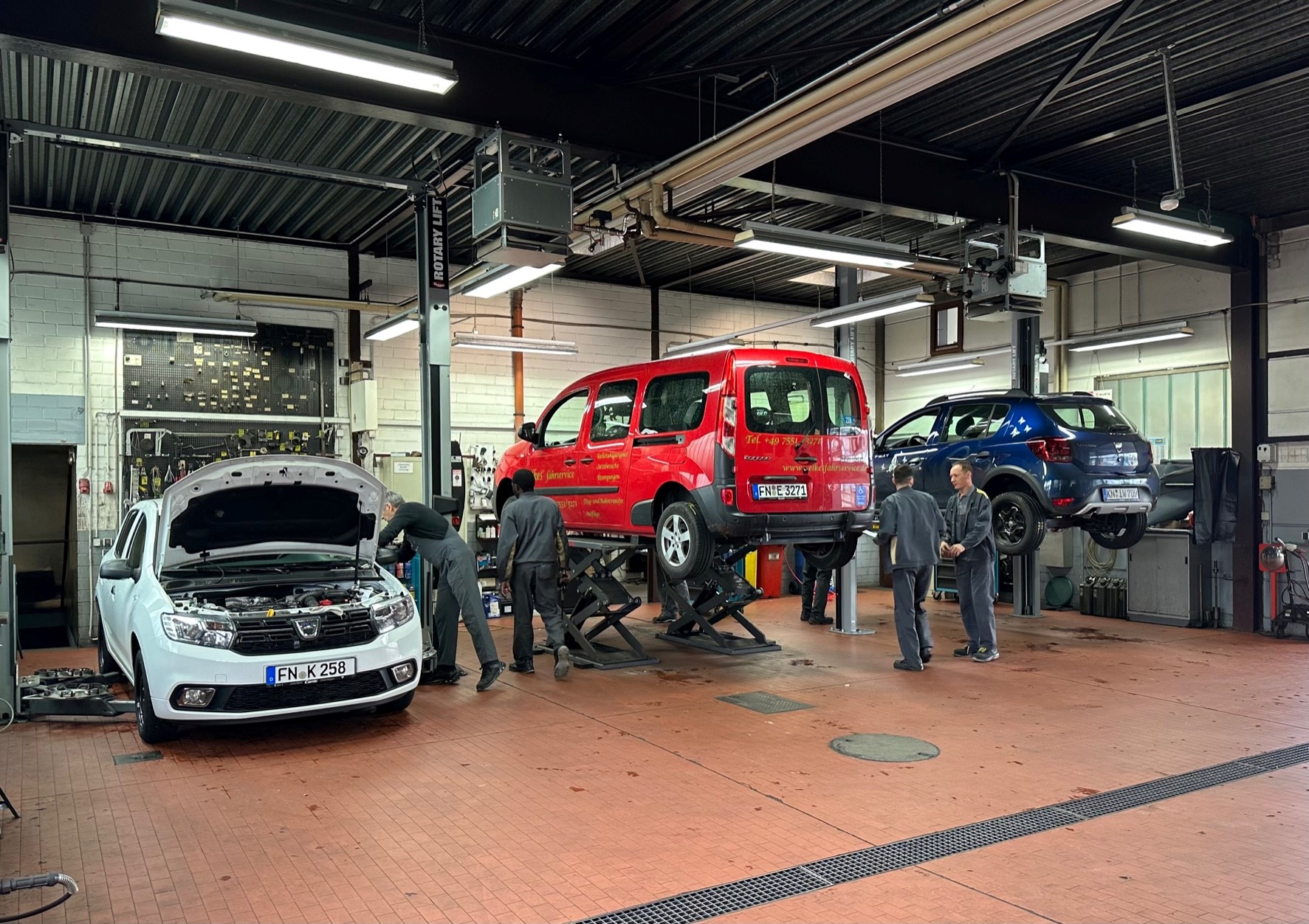 Werkstatt mit mehreren Autos und Mechanikern